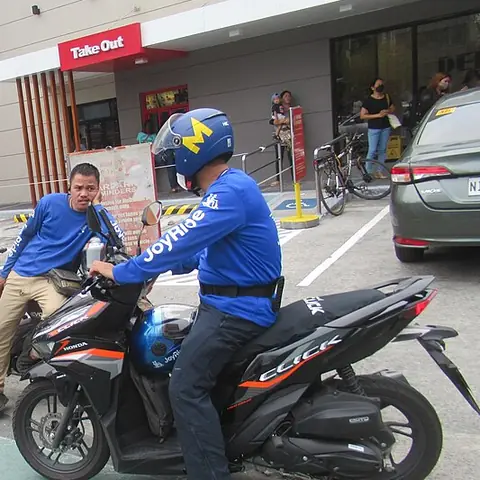 Motorcycle taxi riders in blue jackets on a street in the Philippines