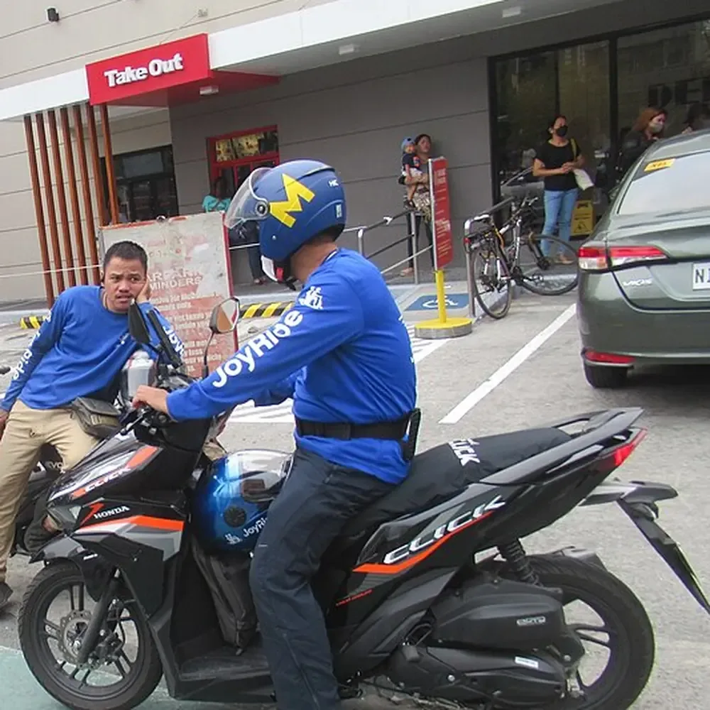 Riders and a delivery motorcycle at a city street